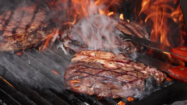 Searing and flipping ribeye steaks on grill