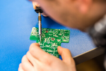 Technician working, soldering on electrical equipment, logic board, pcb. A student of electrical...