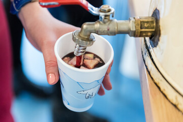 Obraz premium Filling a Christmas cup with red alcoholic Christmas punch. Punch sale at the market, party, Christmas party.