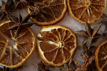 Obraz na płótnie Canvas Dried orange star anise cinnamon close-up. Aniseeds, pimpinella anisum, cinnamon sticks and dried slices of an orange fruit. Spicy orange background. 
