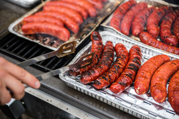 Traditional grilled sausages by a male chef. Barbecue party for guests in the summer in the garden.