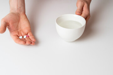 taking morning medicine pill, tablets in hand and water glass