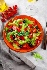  Simple summer salad of lettuce, tomatoes with olives and olive oil on a red plate vertical photo