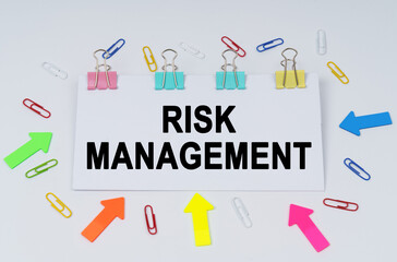 On the table there are paper clips and directional arrows, a sign that says - Risk Management