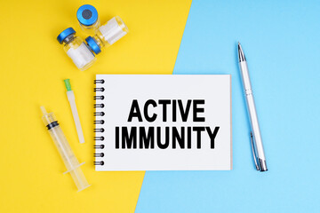 A syringe, ampoules and a notebook with the inscription - ACTIVE IMMUNITY