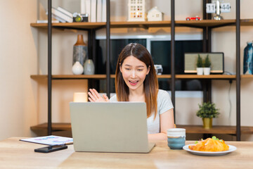 Asian woman using laptop making video call for distant meeting or online support working from home...