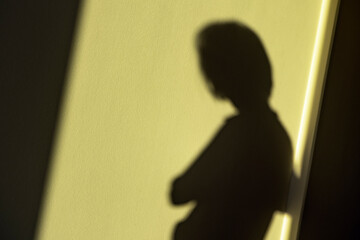 Woman shadow on yellow wall as mental health, lonely person concept, no focus, smooth shut