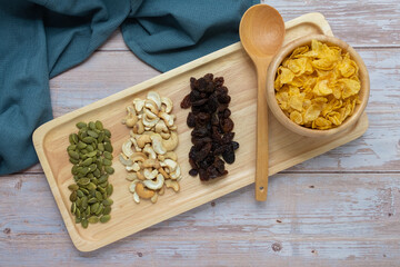 Grains in wooden tray, Currant,Cashew nut,Pumpkin seed,And Cornflakes in wooden cup on wooden floor background.