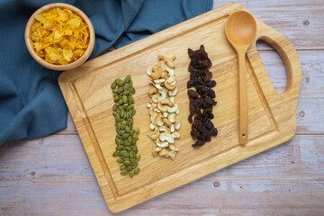 Grains in wooden tray, Currant,Cashew nut,Pumpkin seed,And Cornflakes in wooden cup on wooden floor background.