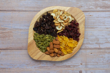 Grains in wooden circle tray, Currant,Cashew nut ,Almond,Pumpkin seed,Cranberry dried fruit, And Cornflakes on wooden floor background.