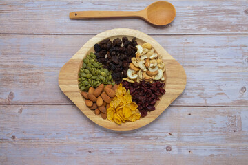 Grains in wooden circle tray, Currant,Cashew nut ,Almond,Pumpkin seed,Cranberry dried fruit, And Cornflakes on wooden floor background.