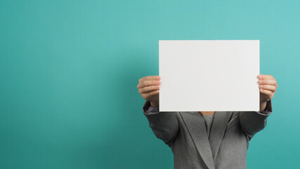 Blank empty paper in woman hand and wear suit on mint or Tiffany Blue background.asian people