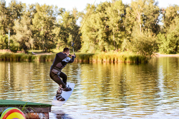 Fototapeta na wymiar A man wakeboarding on a lake on summer day in a life jacket. Soft focus. Action blur.