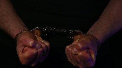 Man with cuffed hands in police lights