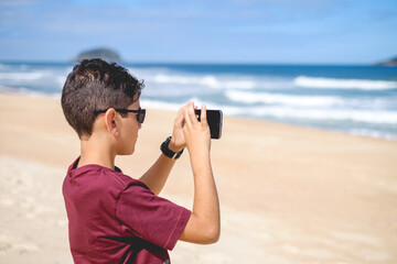 teenager taking picture with smartphone on the beach