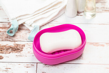 soap on pink plastic soap dish with towels on white wooden table in bathroom