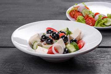 Fresh delicious Greek salad with tomato, cucumber, onions and olives with olive oil