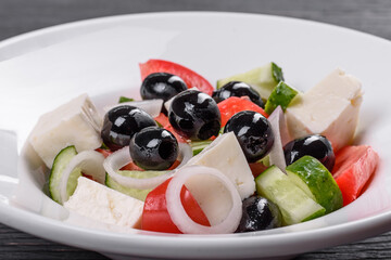 Fresh delicious Greek salad with tomato, cucumber, onions and olives with olive oil