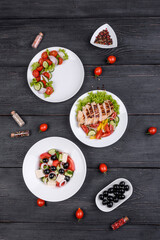 Three fresh delicious salads with chicken, tomato, cucumber, onions and greens with olive oil