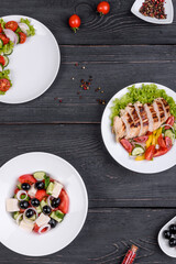 Three fresh delicious salads with chicken, tomato, cucumber, onions and greens with olive oil