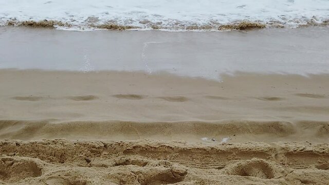 Vague qui recouvre le sable et les traces