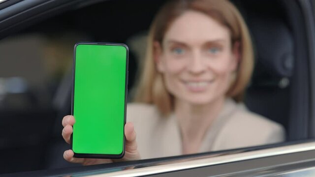 Woman sitting in car at dealership and holding smartphone