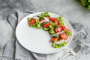 Fresh delicious salad with vegetables: tomato, cucumber, onions and greens with olive oil
