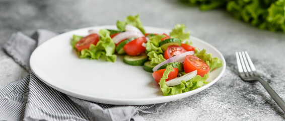 Fresh delicious salad with vegetables: tomato, cucumber, onions and greens with olive oil