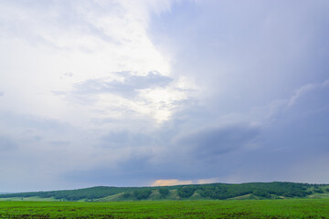 Fototapeta na wymiar Blue sky and green meadow with mountains.