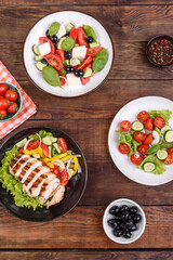 Three fresh delicious salads with chicken, tomato, cucumber, onions and greens with olive oil