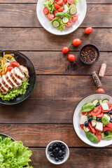 Three fresh delicious salads with chicken, tomato, cucumber, onions and greens with olive oil