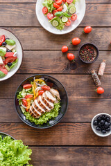 Three fresh delicious salads with chicken, tomato, cucumber, onions and greens with olive oil