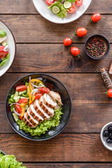 Three fresh delicious salads with chicken, tomato, cucumber, onions and greens with olive oil
