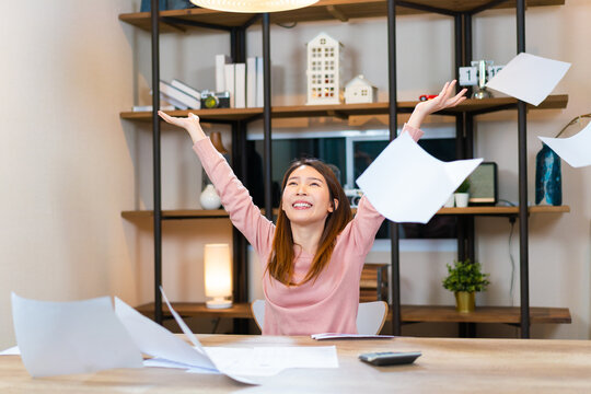Cheerful Asian woman working on desk. Female success the job throwing paper sheets on the air. Happiness and successful concept.