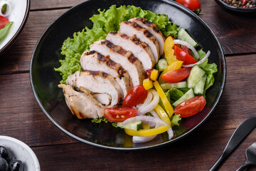 Fresh delicious salad with chicken, tomato, cucumber, onions and greens with olive oil