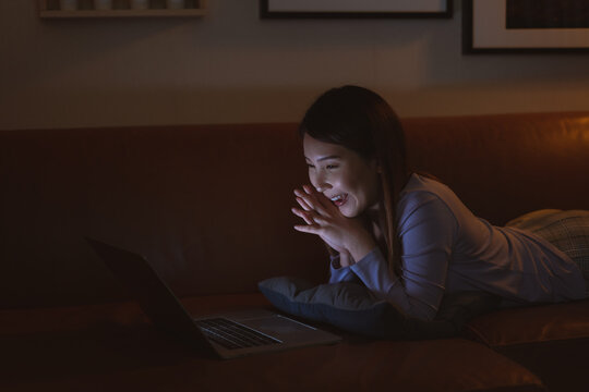 Asian woman watching online film on laptop at night