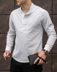 Stylish handsome model man in casual clothes lifestyle in the street with watch and leather clutch