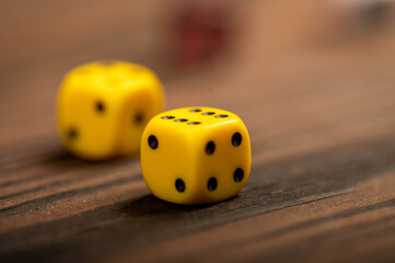 Yellow dice scattered on a wooden table. Close-up, selective focus.