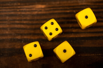 Yellow dice scattered on a wooden table. Close-up, selective focus.