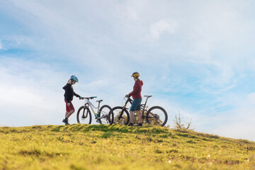 Fototapeta na wymiar Two females on mountain bikes talking and looking at beautiful sunset