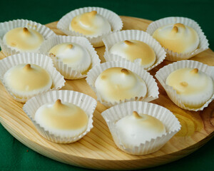 Several and Delicious French dessert Meringues into a silicone form moulds on a round wooden plate
