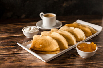 Breakfast. Russian pancakes with sour cream and jam. A cup of espresso.