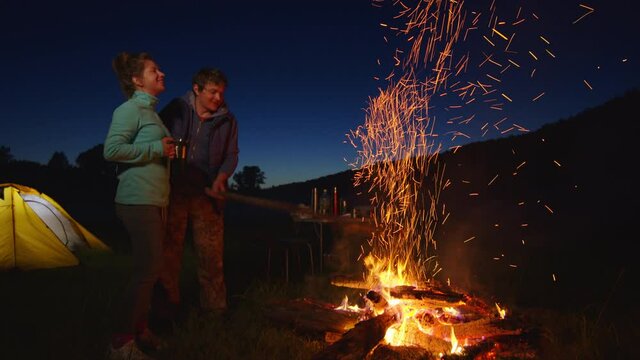 Camping couple. Couple camping in the wild and stand near the bright bonfire with tent and car on the background