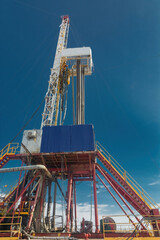 Drilling rig for drilling wells for oil and gas. General detailed view. View from the side from bottom to top.  Drill tower on the base and drill pipes for lowering into the well