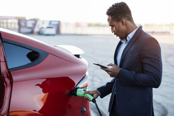 Close up of african american businessman in suit using modern smartphone while standing outdoors...