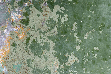 Green peeling paint on the wall. Old concrete wall with cracked flaking paint. Weathered rough painted surface with patterns of cracks and peeling. High resolution texture for background and design.