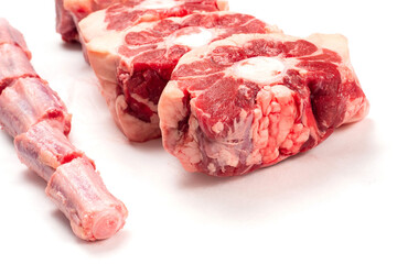 Raw uncooked beef oxtail cut into portions on white isolated background. Butcher craft. Meat industry product. Soup and stew ingredient