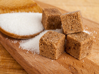 brown diced cane sugar, refined sugar, white sugar on a wooden plate, sugar consumption concept, easily digestible carbohydrates