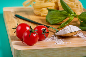 three cherry tomatoes in the foreground with a tablespoon of flour
