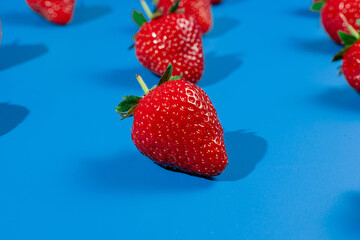 Strawberry ripe fruit on blue background. Harvest of fresh red berry